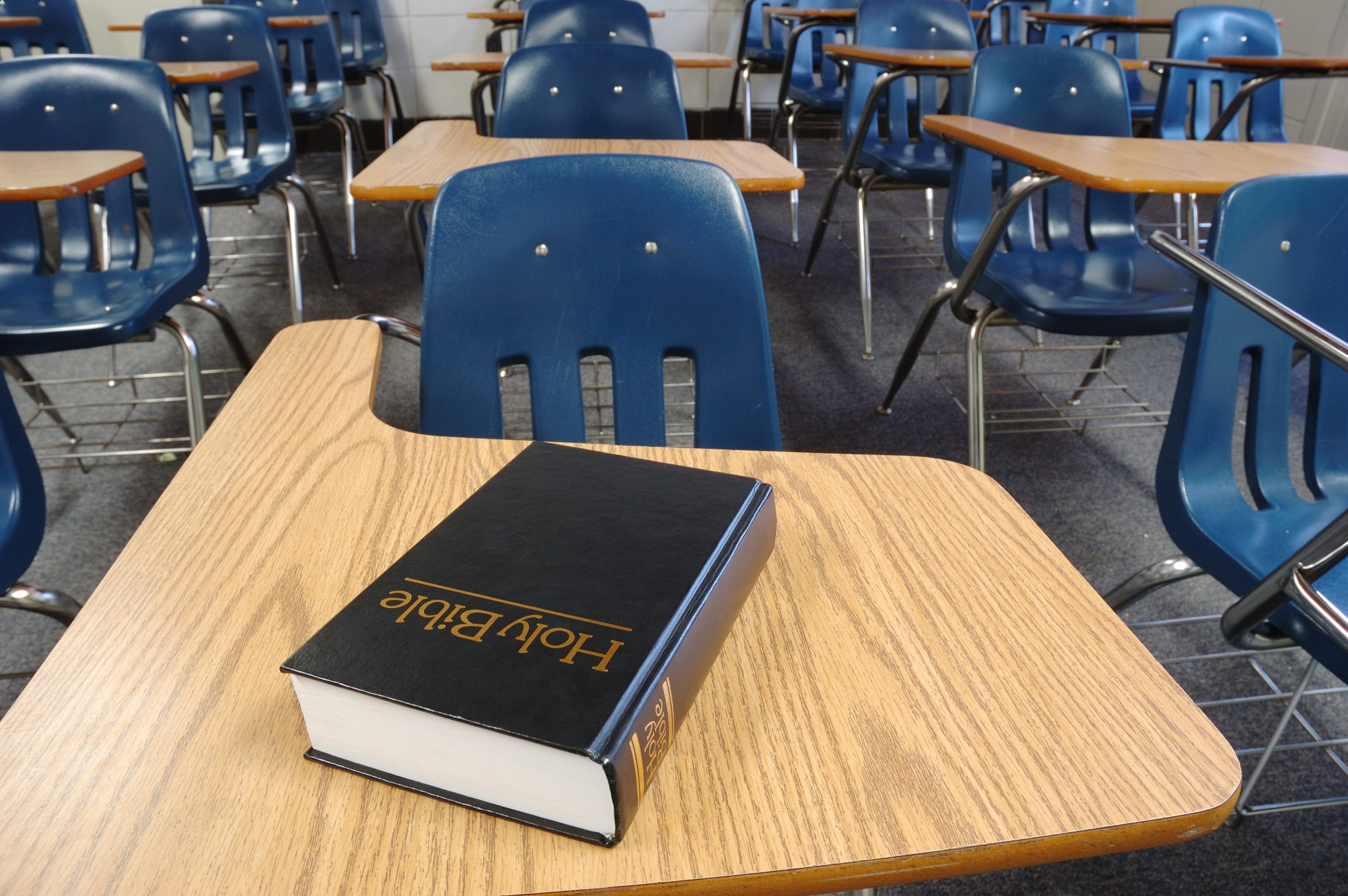 Bible on desk in empty classroom.