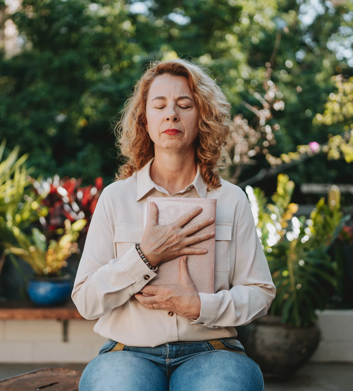 Woman meditating with book in garden.
