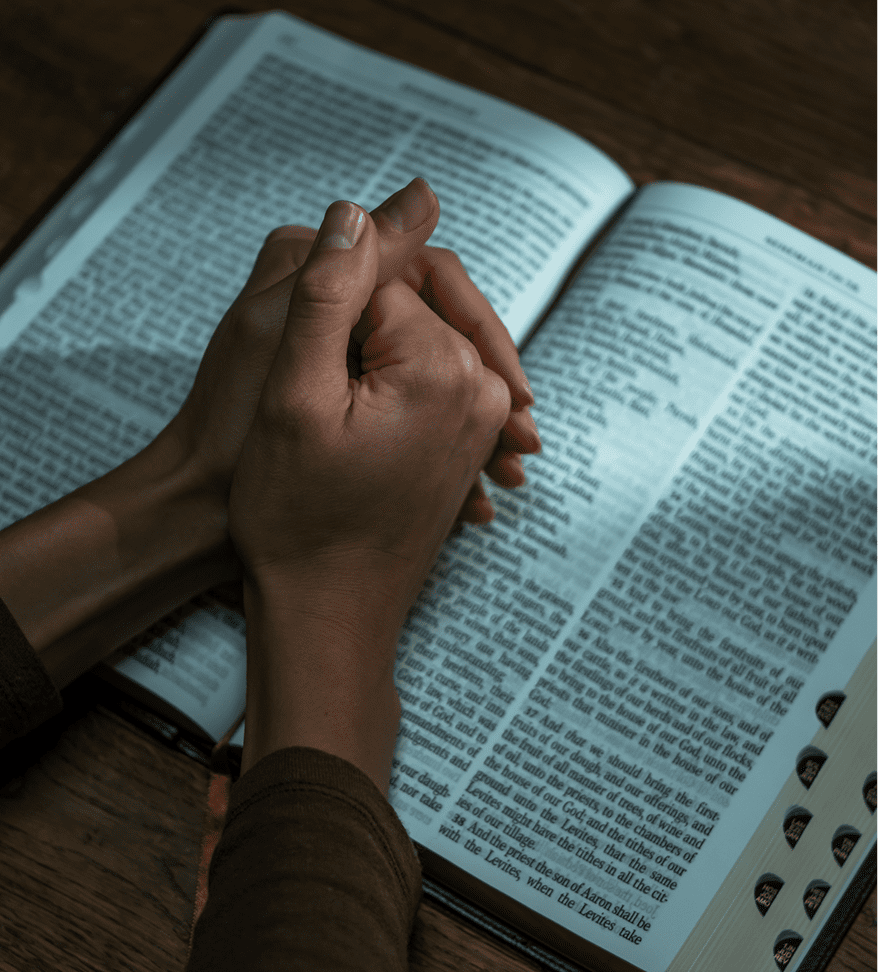 Hands clasped over an open book.