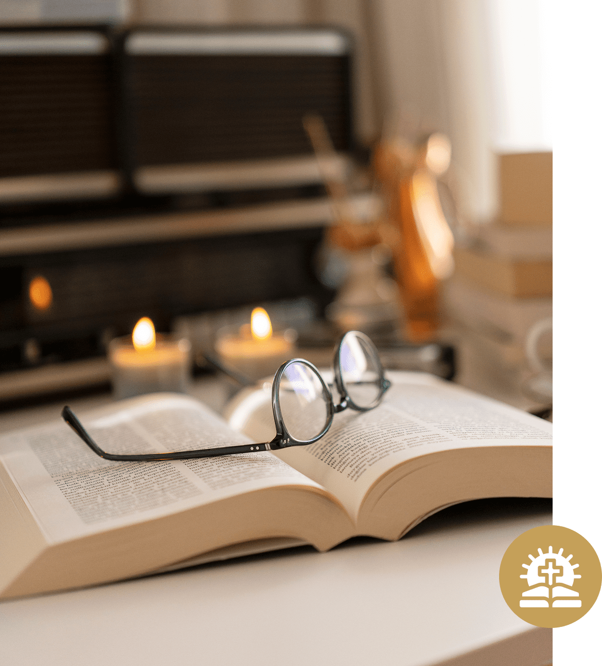 Glasses on open book with candles nearby.