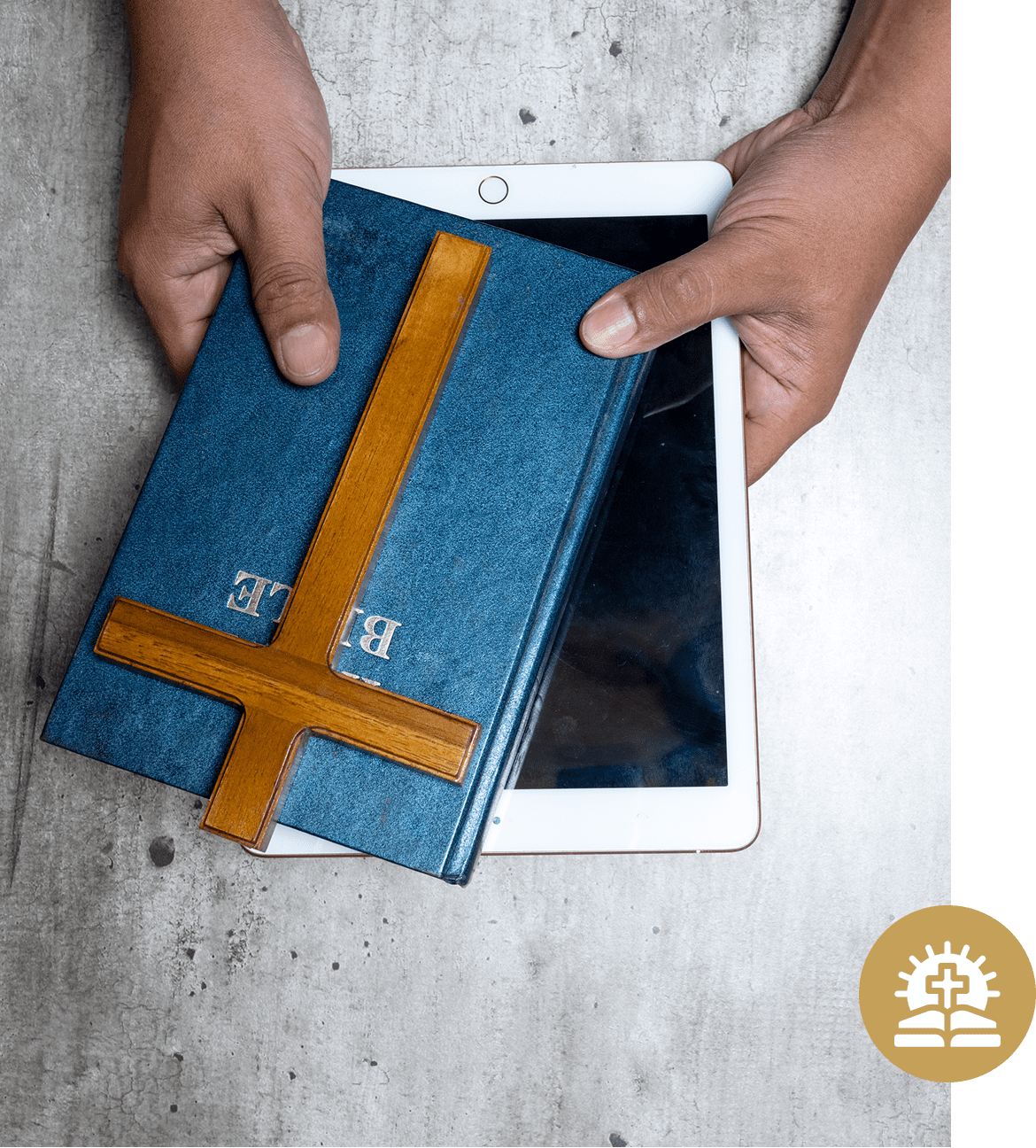 Hands holding a Bible and tablet.