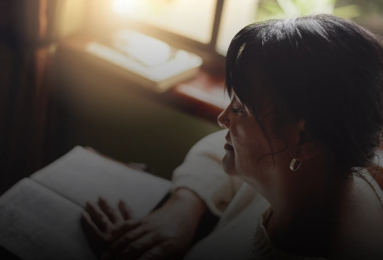Woman reading by a sunlit window.